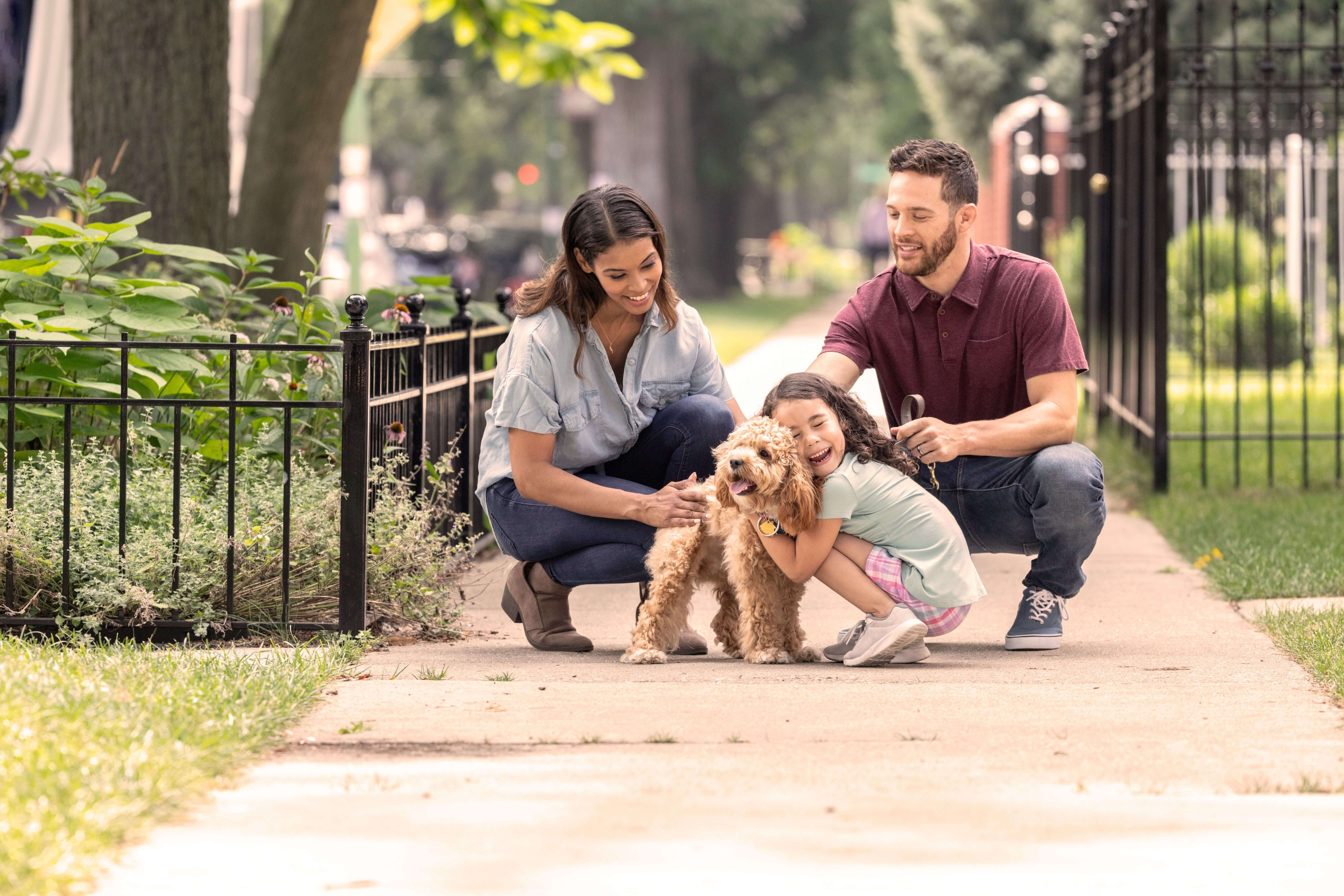 Husband and wife with baby girl cuddling dog